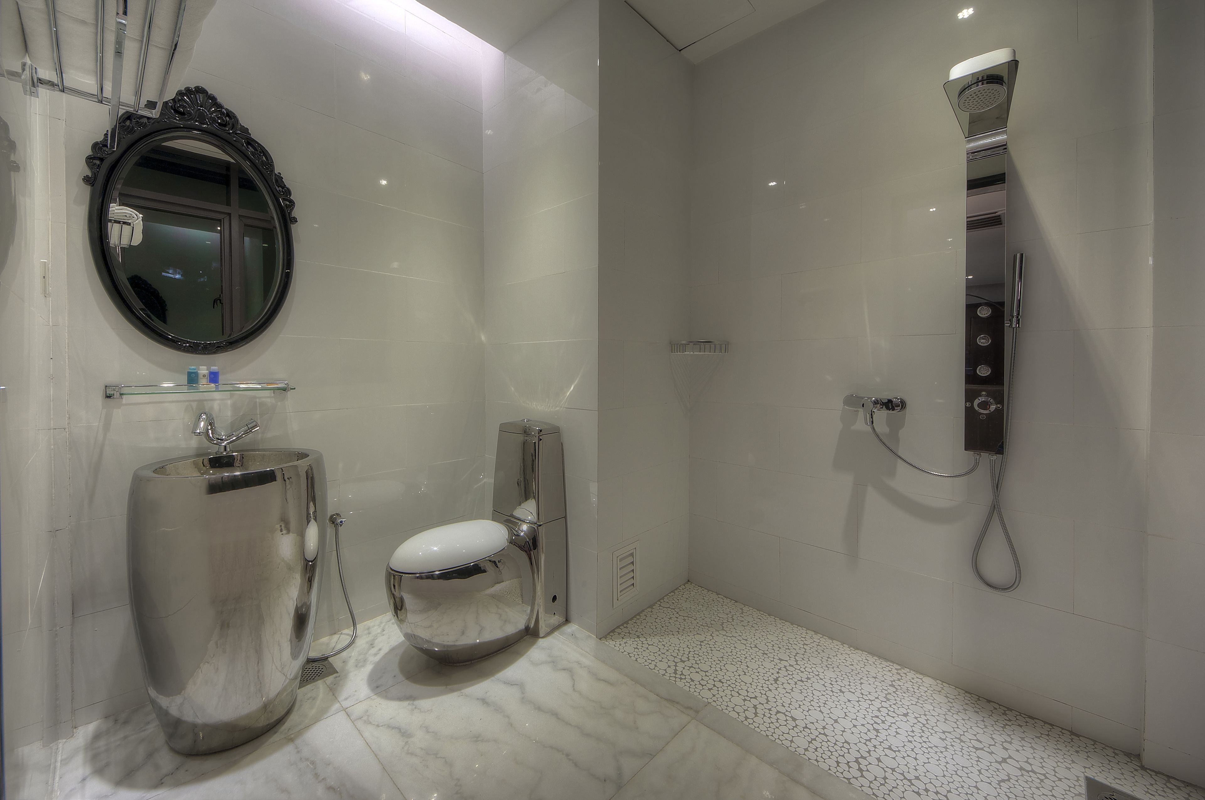 Un baño moderno con un espejo grande, un inodoro y una ducha.