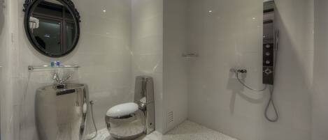 Un baño moderno con un espejo grande, un inodoro y una ducha.