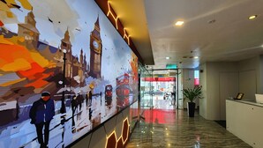 Eine Hotellobby mit einer großen digitalen Wandmalerei einer Stadtansicht, einer Rezeption und einer Topfpflanze.