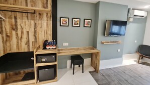 A modern room with a wooden desk, a black office chair, a TV mounted on the wall, and a small fridge. - Arenaa Star (Kuala Lumpur)