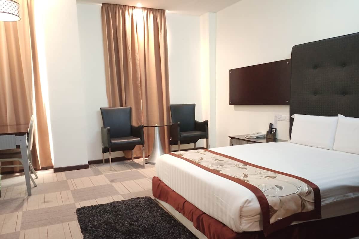 Una habitación de hotel con una cama, dos sillas, un televisor y un escritorio con un teléfono.