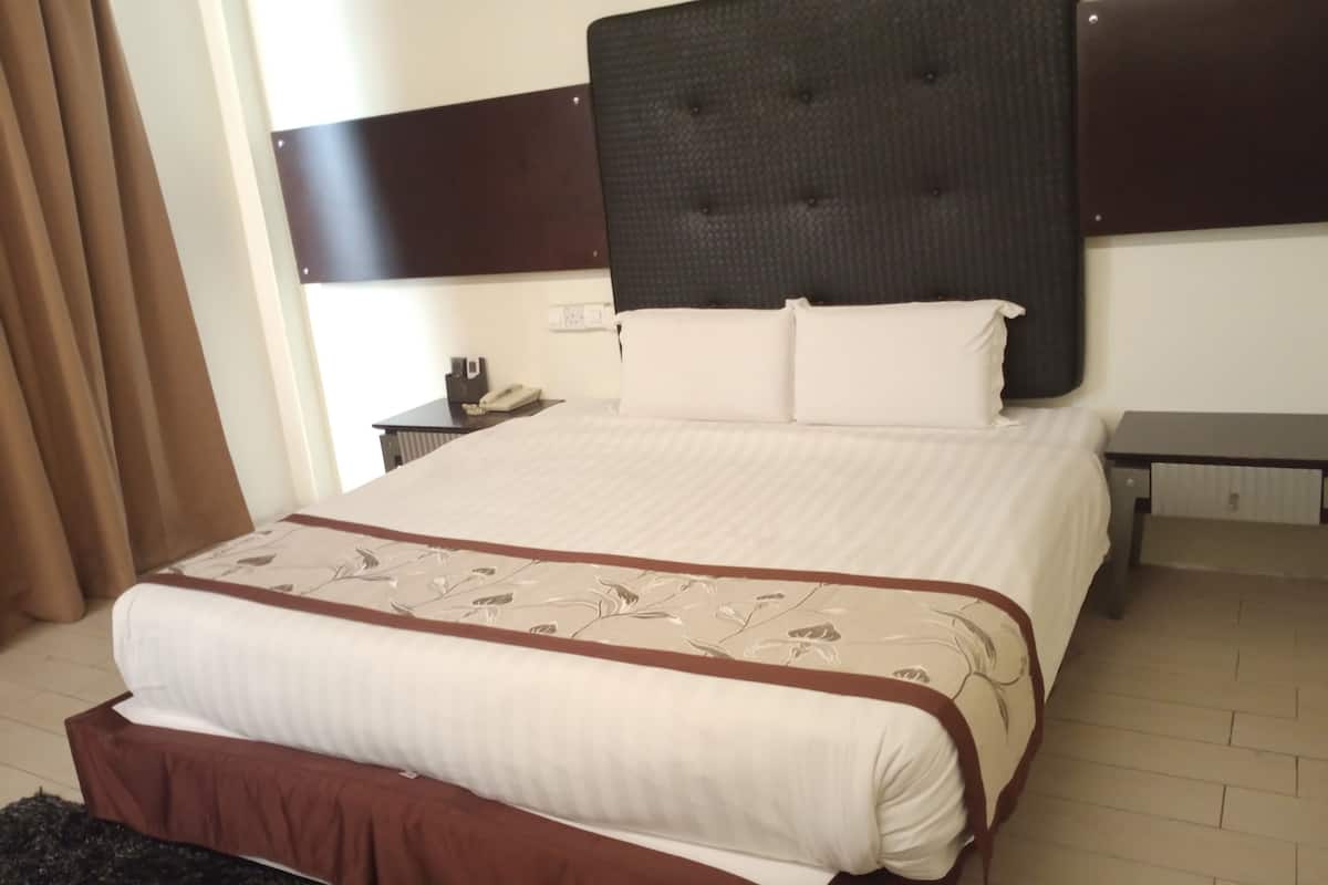 Una habitación de hotel con una cama grande, una mesita de noche con teléfono y un escritorio.
