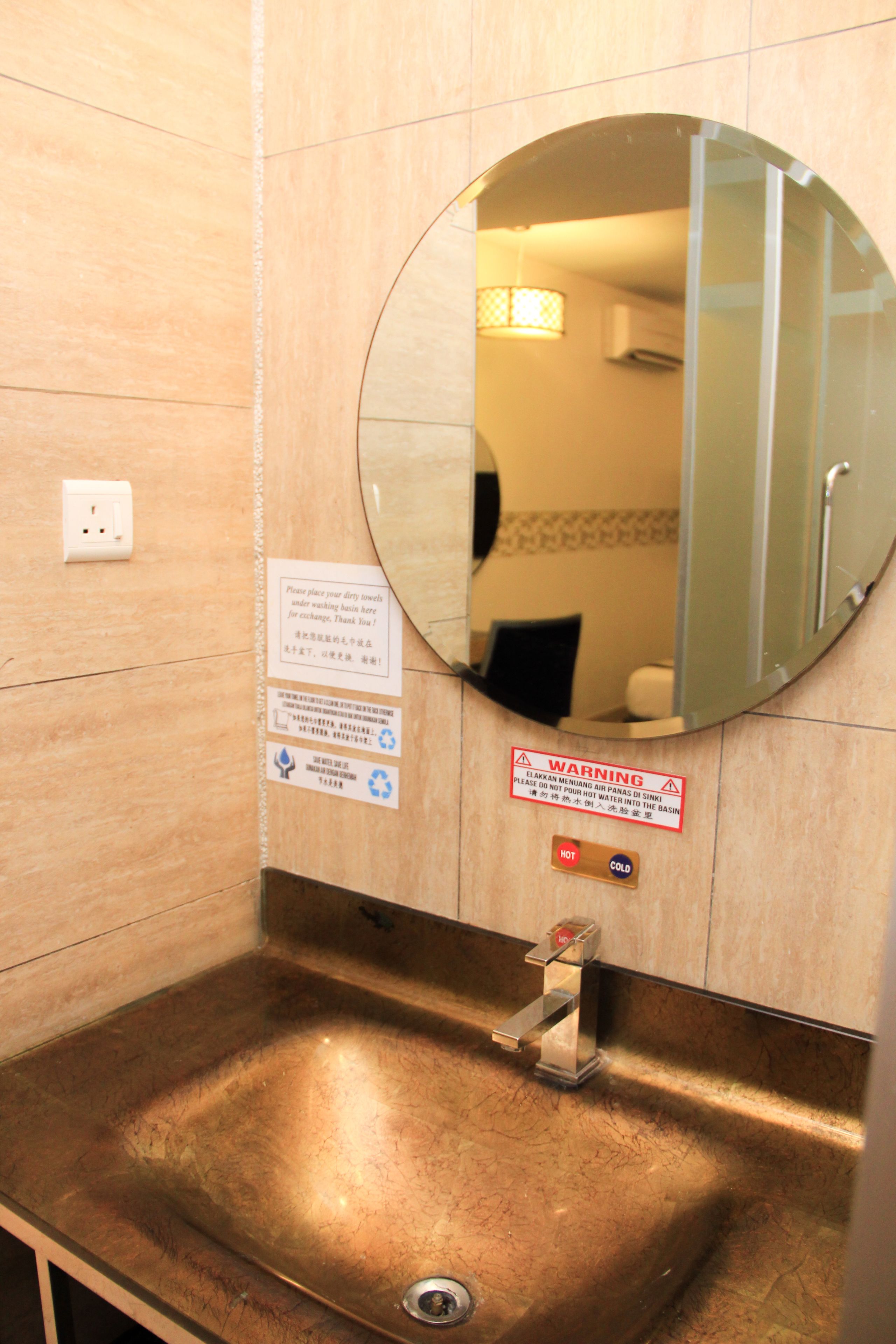 Une salle de bain équipée d’un lavabo, d’un miroir et de panneaux d’avertissement.