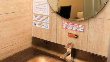 Une salle de bain équipée d’un lavabo, d’un miroir et de panneaux d’avertissement.