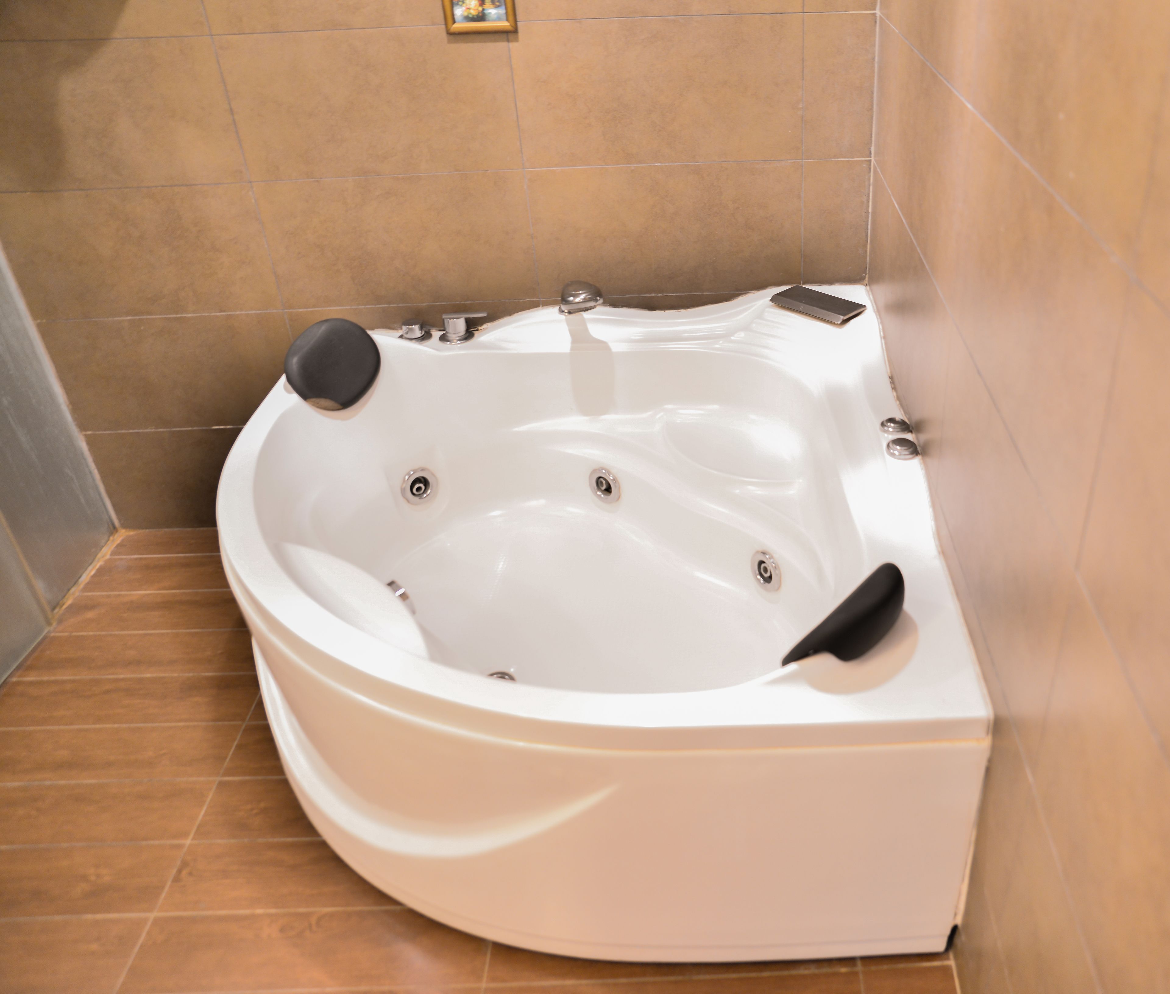 A white jacuzzi in a bathroom with tiled walls and floor.
