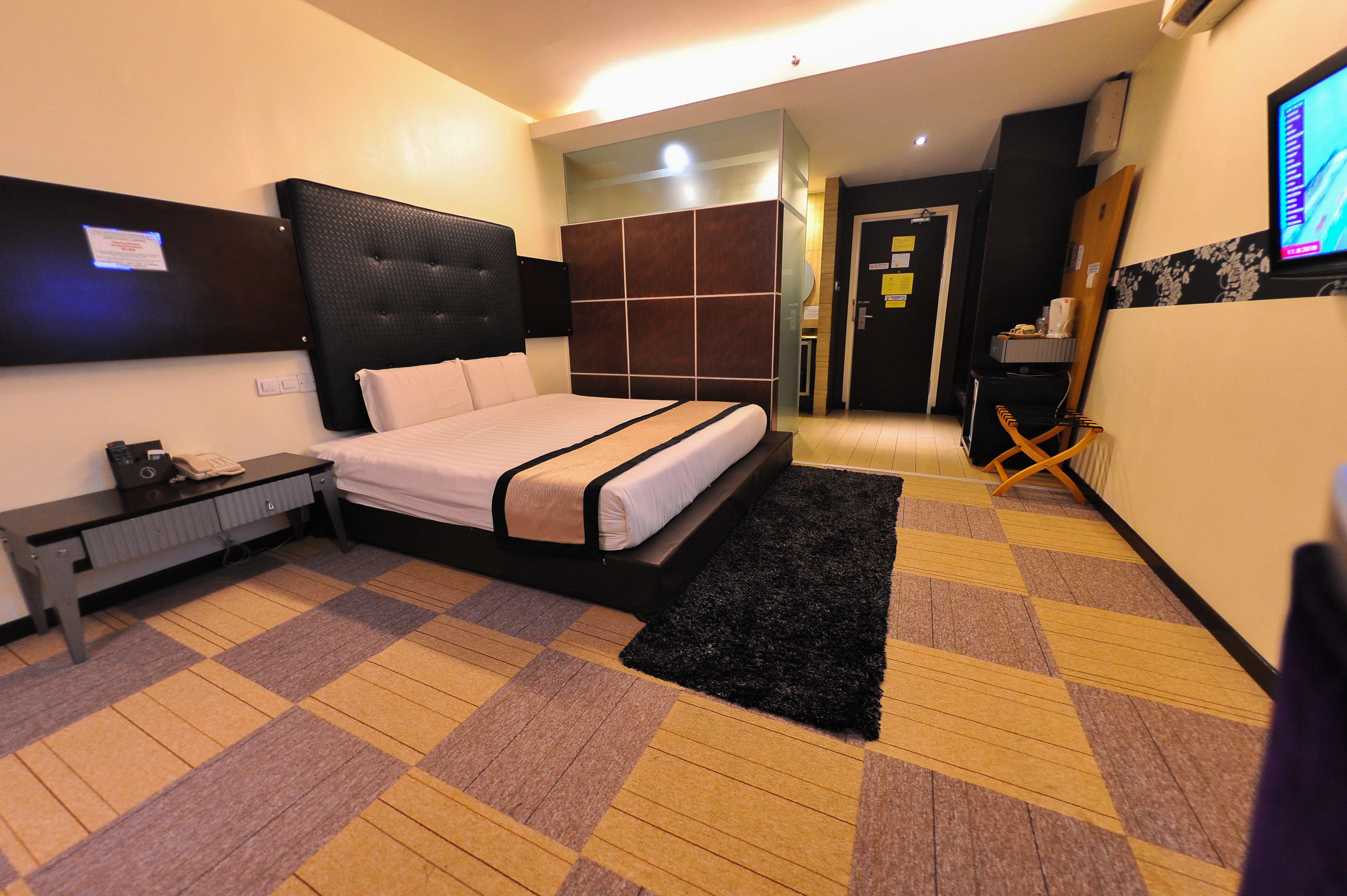 A hotel room with a bed, a desk, a chair, and a TV.