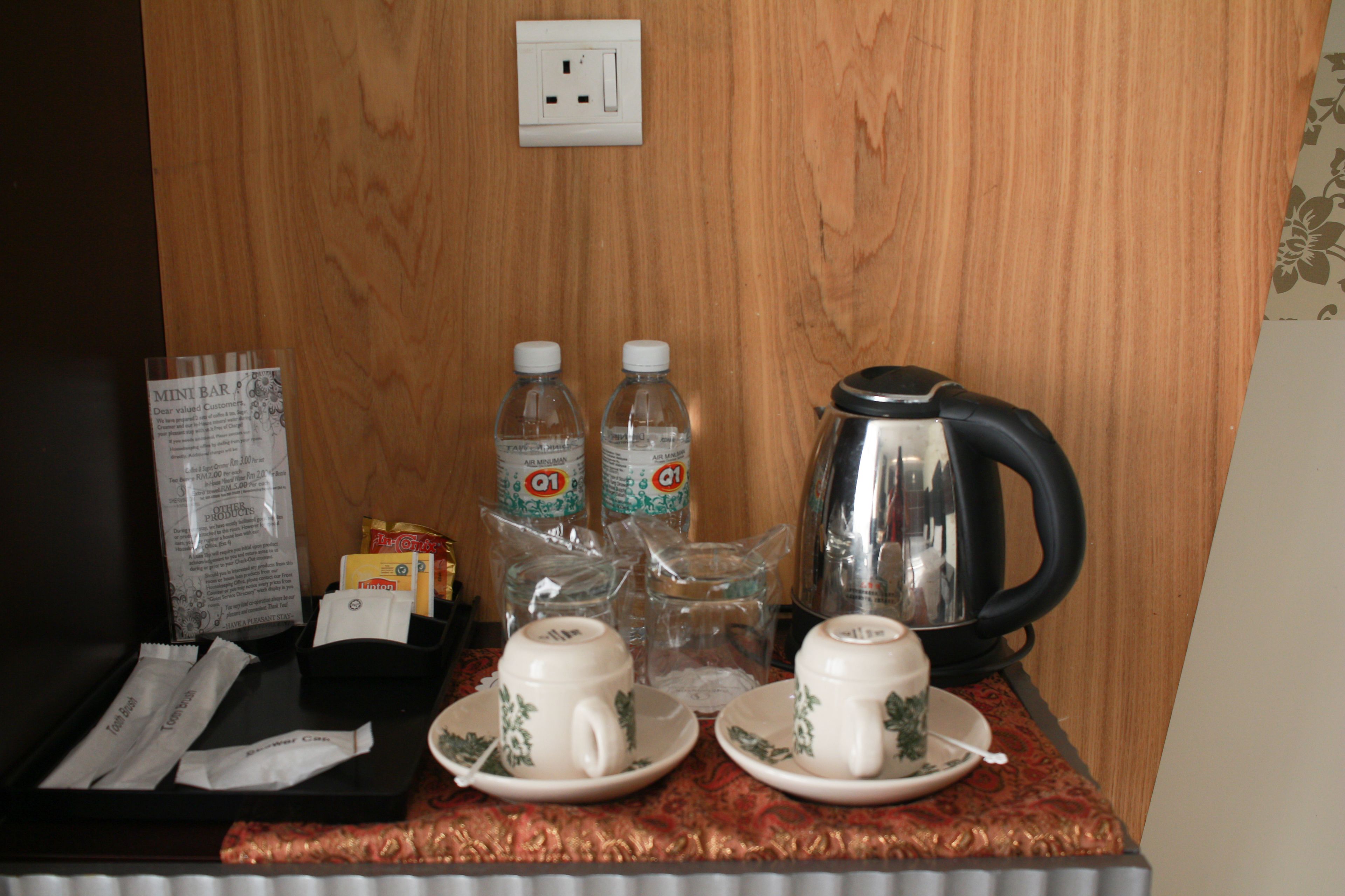 Preparación para el desayuno en una habitación de hotel, con una bandeja, dos tazas, dos botellas de agua, un hervidor y un menú.