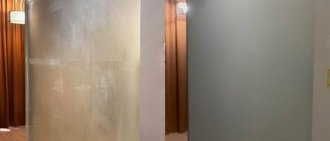 A hallway with a frosted glass partition, wooden flooring, and a door with a light switch.