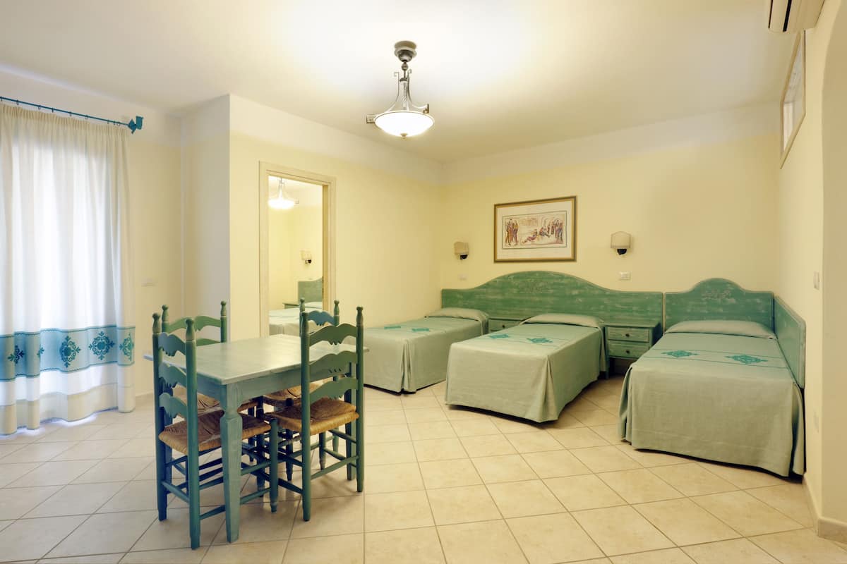 Une chambre comprenant une table à manger, deux lits simples et un ventilateur de plafond.
