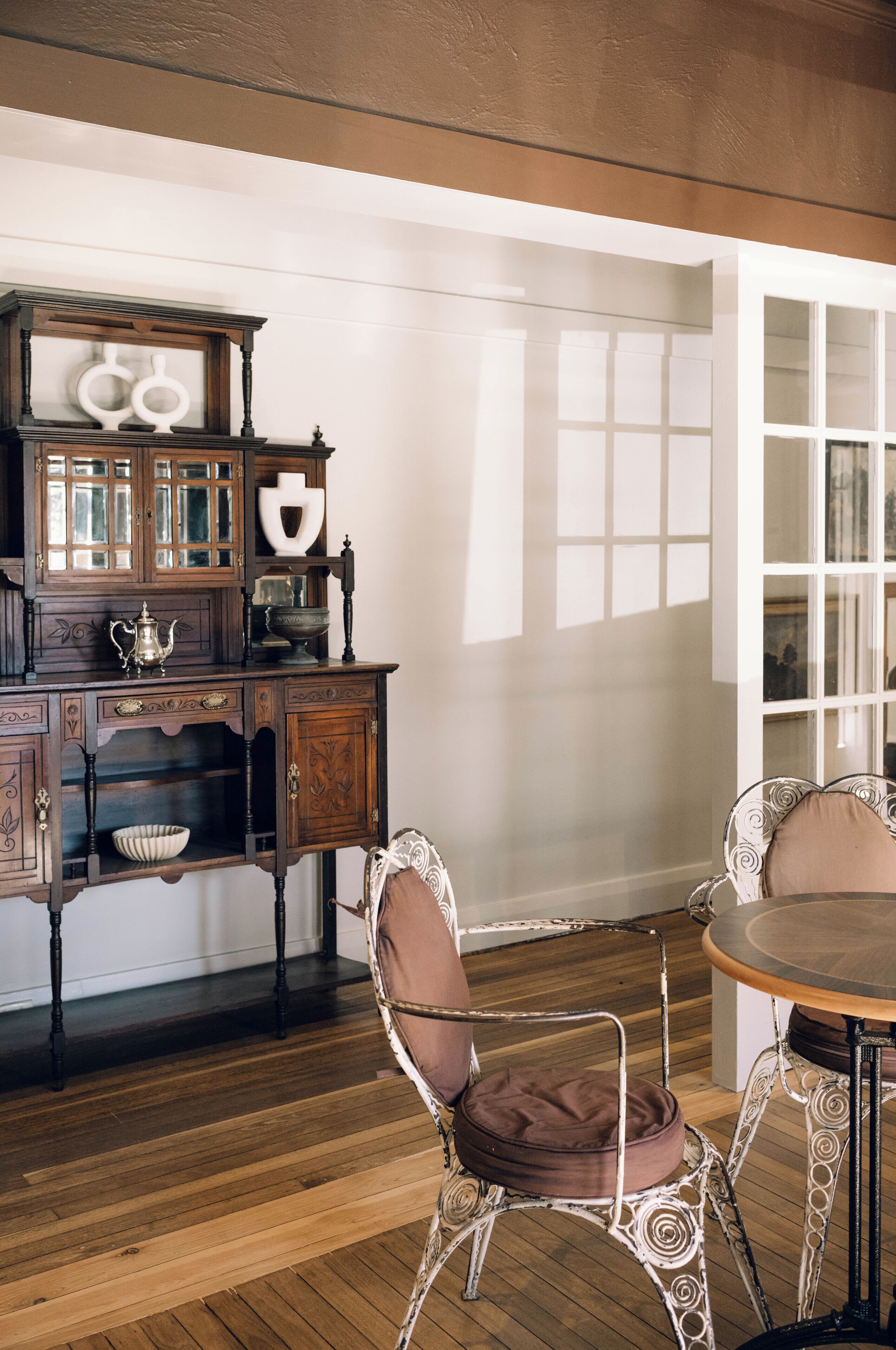 A dining area with a wooden table and chairs, a cabinet with glass doors, and a view of a white door.