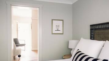 A hotel room with a bed, a chair, a lamp, and a framed picture on the wall.