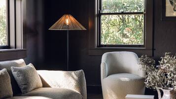 Ett mysigt rum med en soffa, en fåtölj, ett runt bord och en golvlampa.