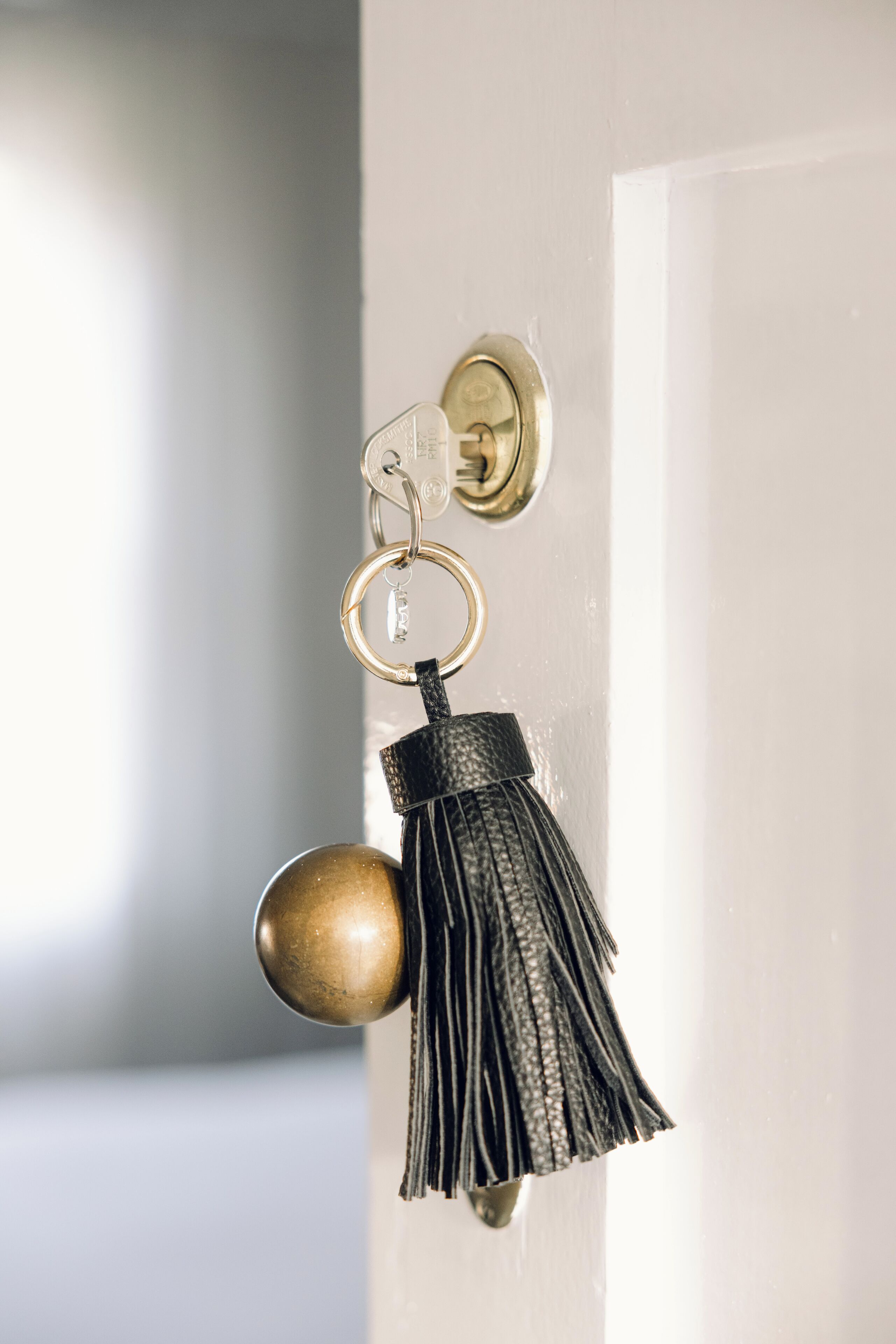 Una puerta con pomo de latón y un llavero con borla.
