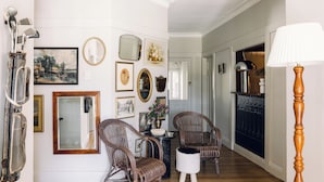 A hallway with wicker chairs, a small table with a vase, and various framed pictures on the wall. - Links House (Burradoo)