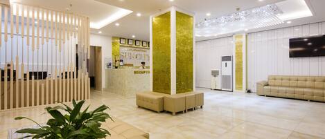 A hotel reception area with a modern design, including a reception desk, seating area, and a large screen.