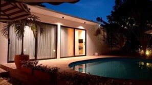 A modern house with a swimming pool, large windows, and a well-lit interior. - Casa Bustamante Hotel Boutique (Cartagena)