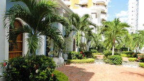 Un patio con palmeras, un camino de ladrillo y un edificio con balcones.