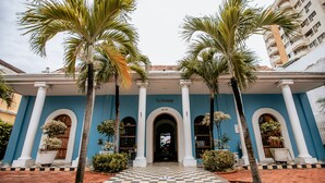 Un edificio con suelo a cuadros, palmeras y fachada azul.