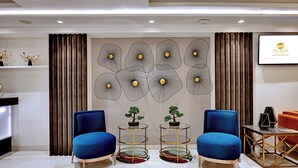 Un vestíbulo moderno con dos sillones azules, un mostrador de recepción y arte decorativo en la pared.