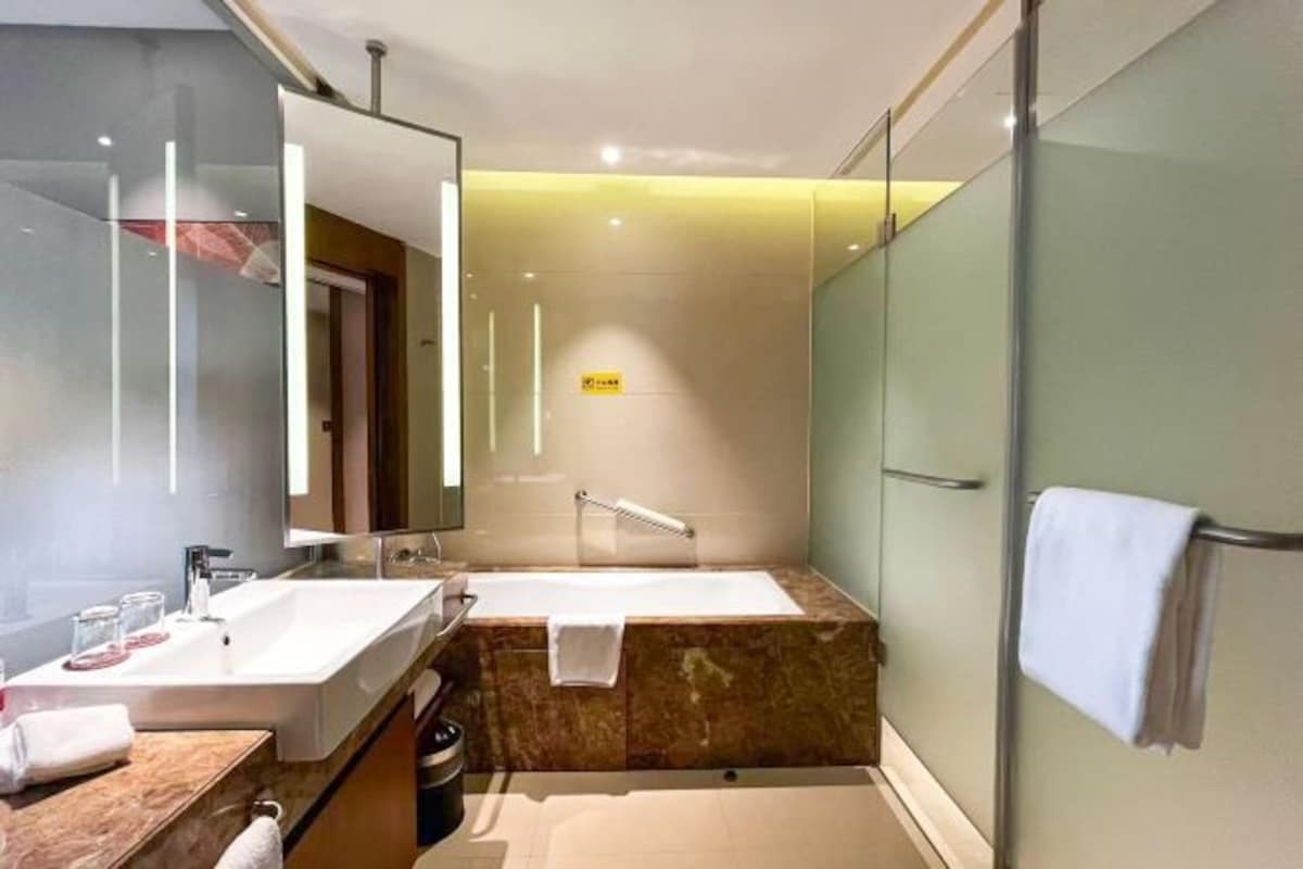 A modern bathroom with a large mirror, a bathtub, and a shower.