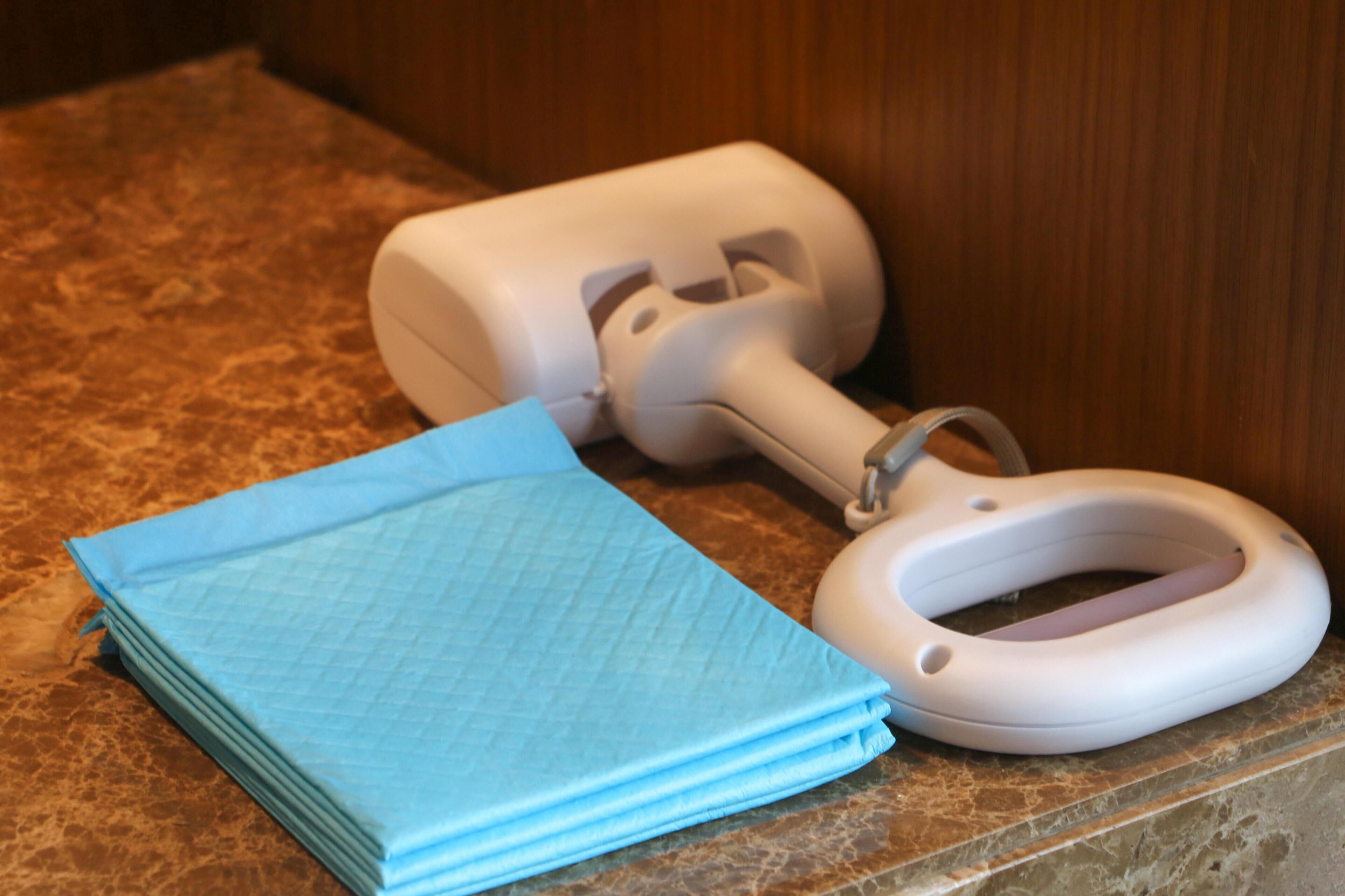 A toilet brush and a stack of blue toilet paper on a granite countertop.