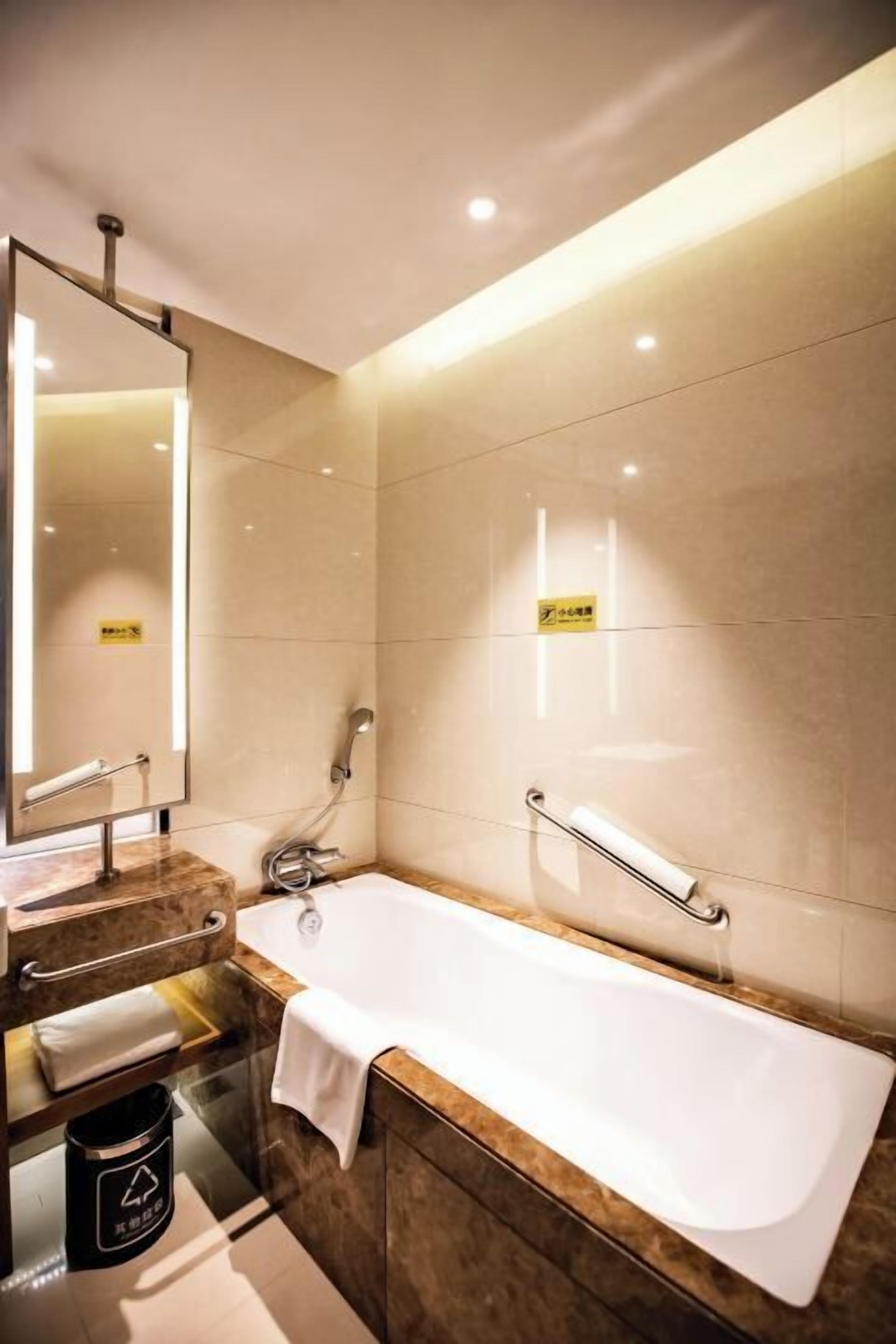 A modern bathroom with a large bathtub, a vanity with a mirror, and a towel rack.