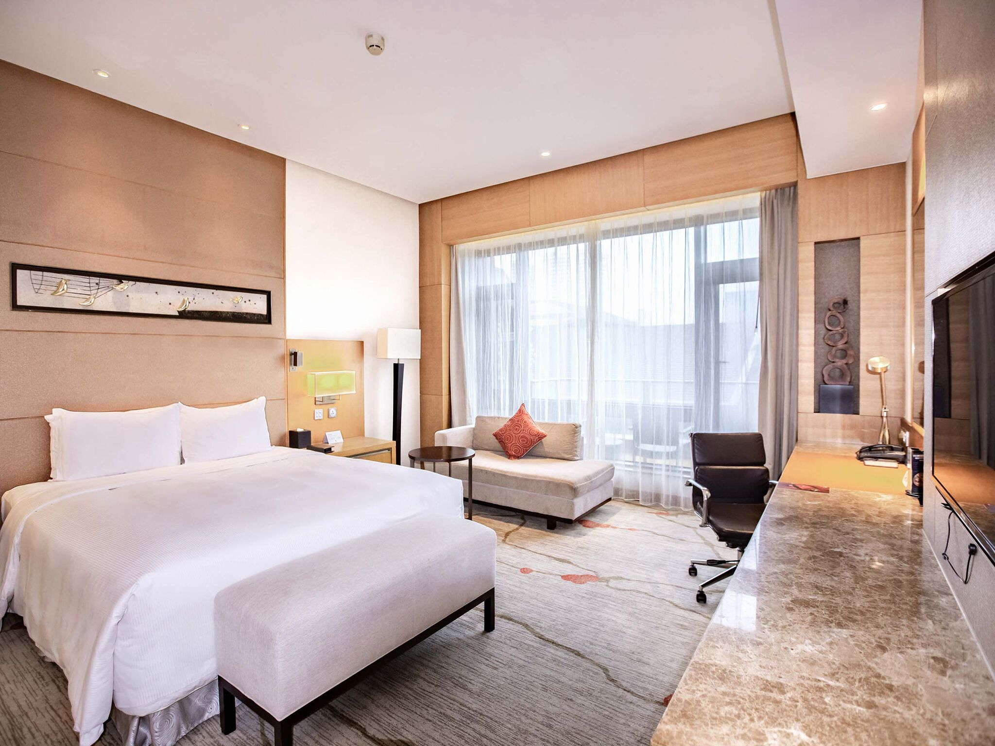 Una moderna camera d'albergo con un letto grande, un divano, una scrivania e una TV.