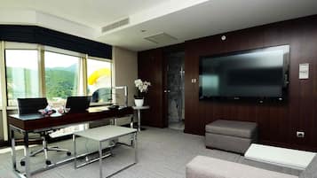 Relax in a spacious room with a large flat-screen TV, comfortable sofa, and a desk for work or relaxation.