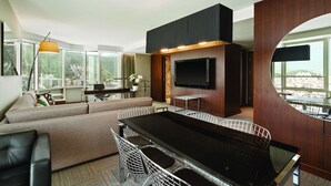 A modern living room with a sofa, dining table, chairs, and a TV.