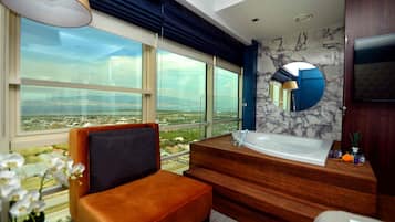 A modern bathroom with a large window, a bathtub, a vanity, and a mirror.
