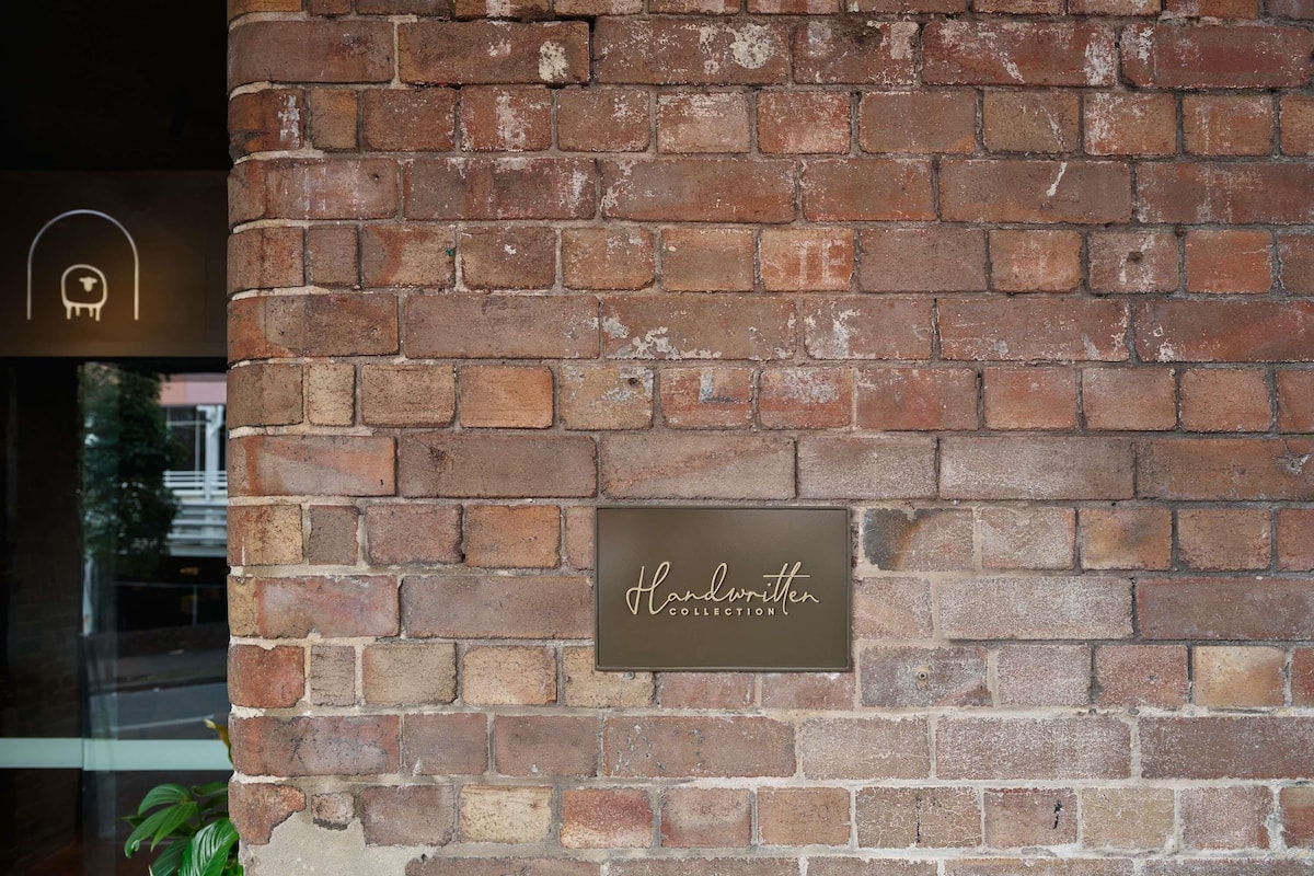 A brick wall with a plaque reading 'Handwritten Collection.'