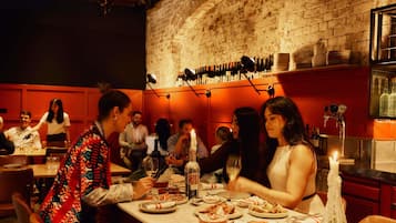 A restaurant with brick walls, tables set with plates and glasses, and bottles on the wall.