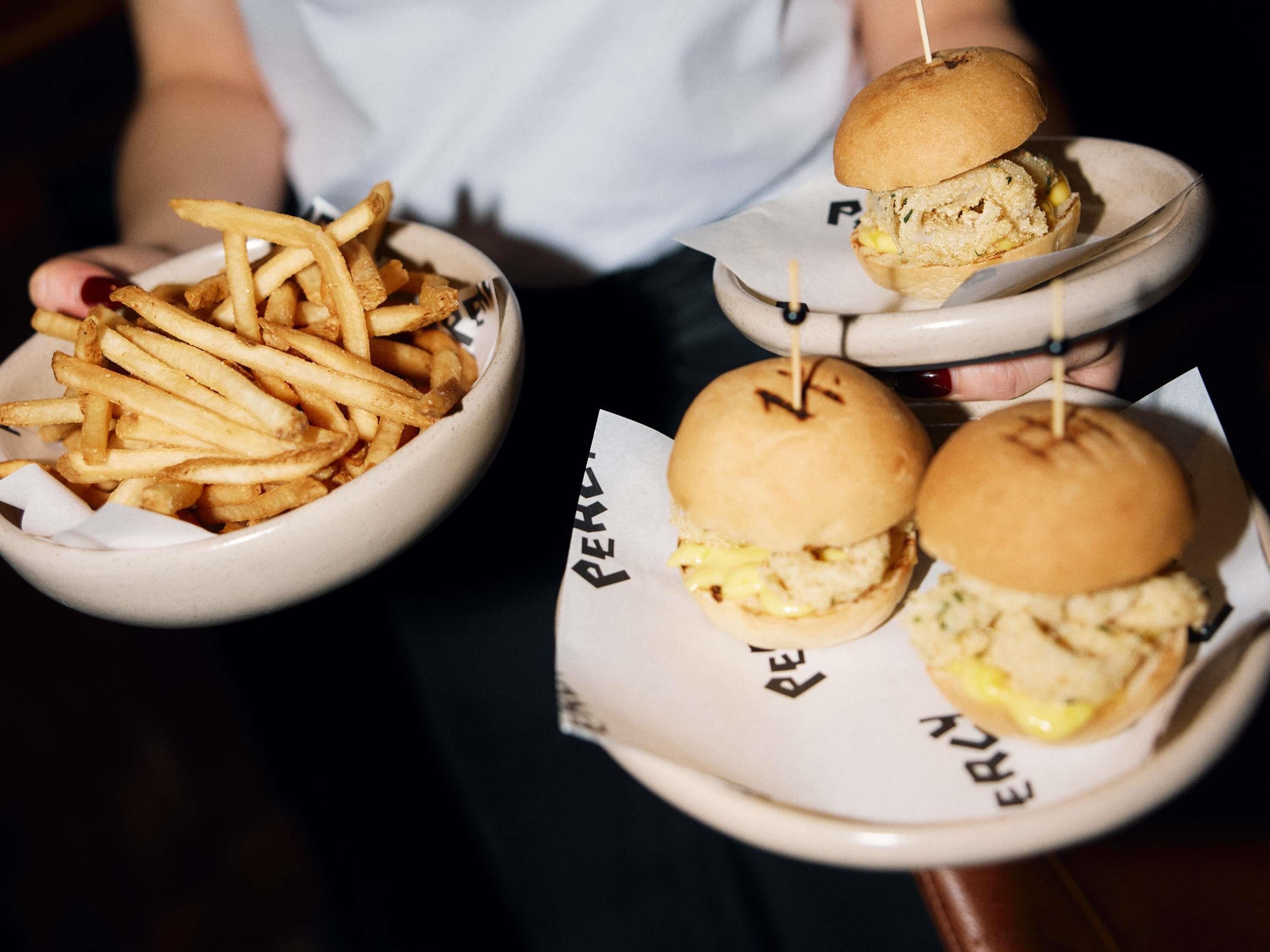 A person holding a plate with a burger and fries.