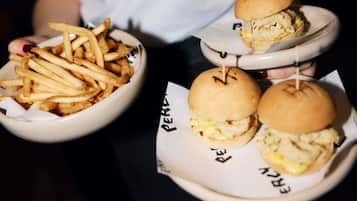 En person som håller i en tallrik med en hamburgare och pommes frites.