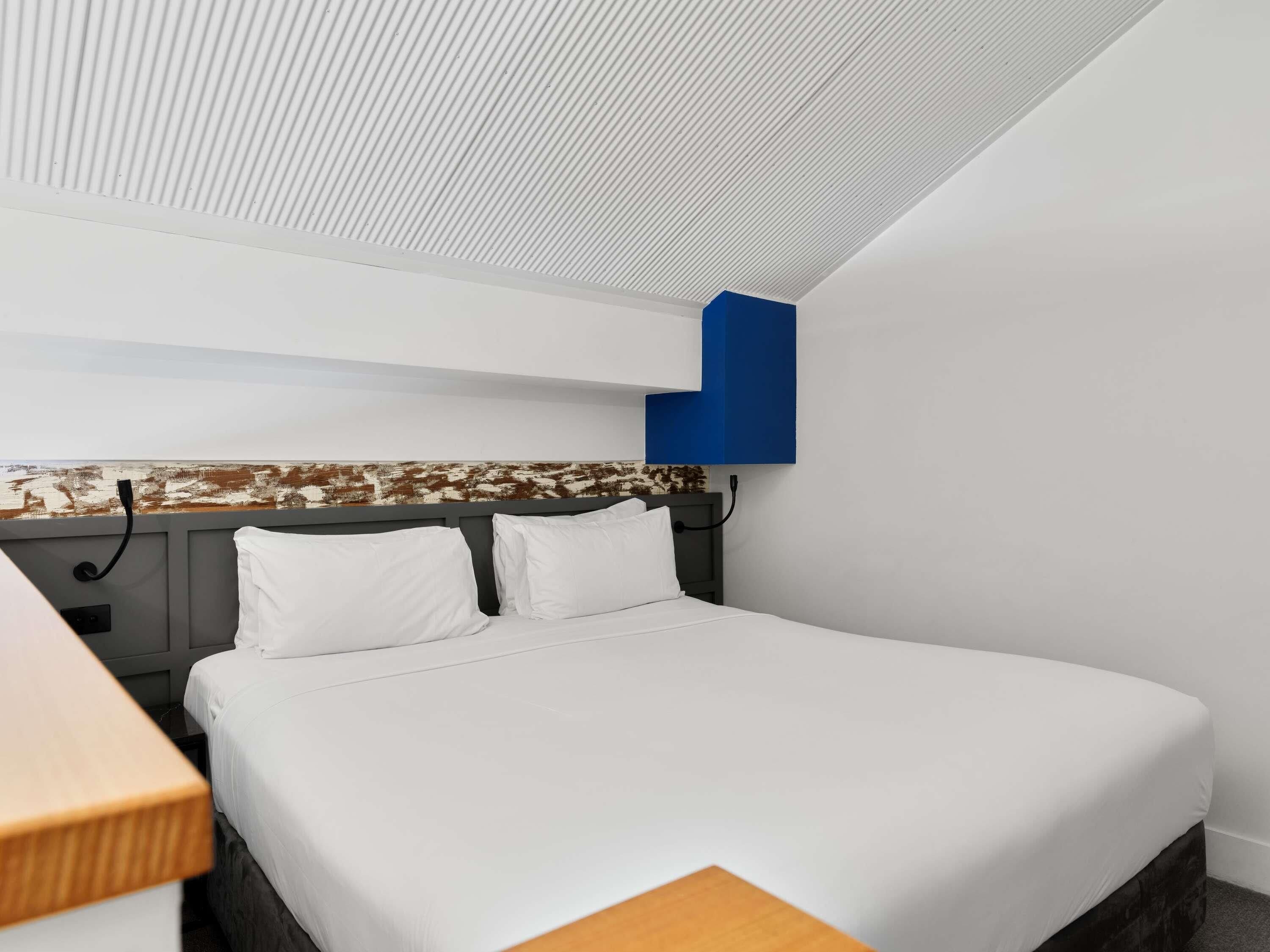 A hotel room with a bed, a desk, and a view of the beach.