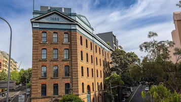 Un edificio storico in mattoni con un'estensione moderna in vetro, con il numero 1888, situato in una strada alberata e con auto parcheggiate.