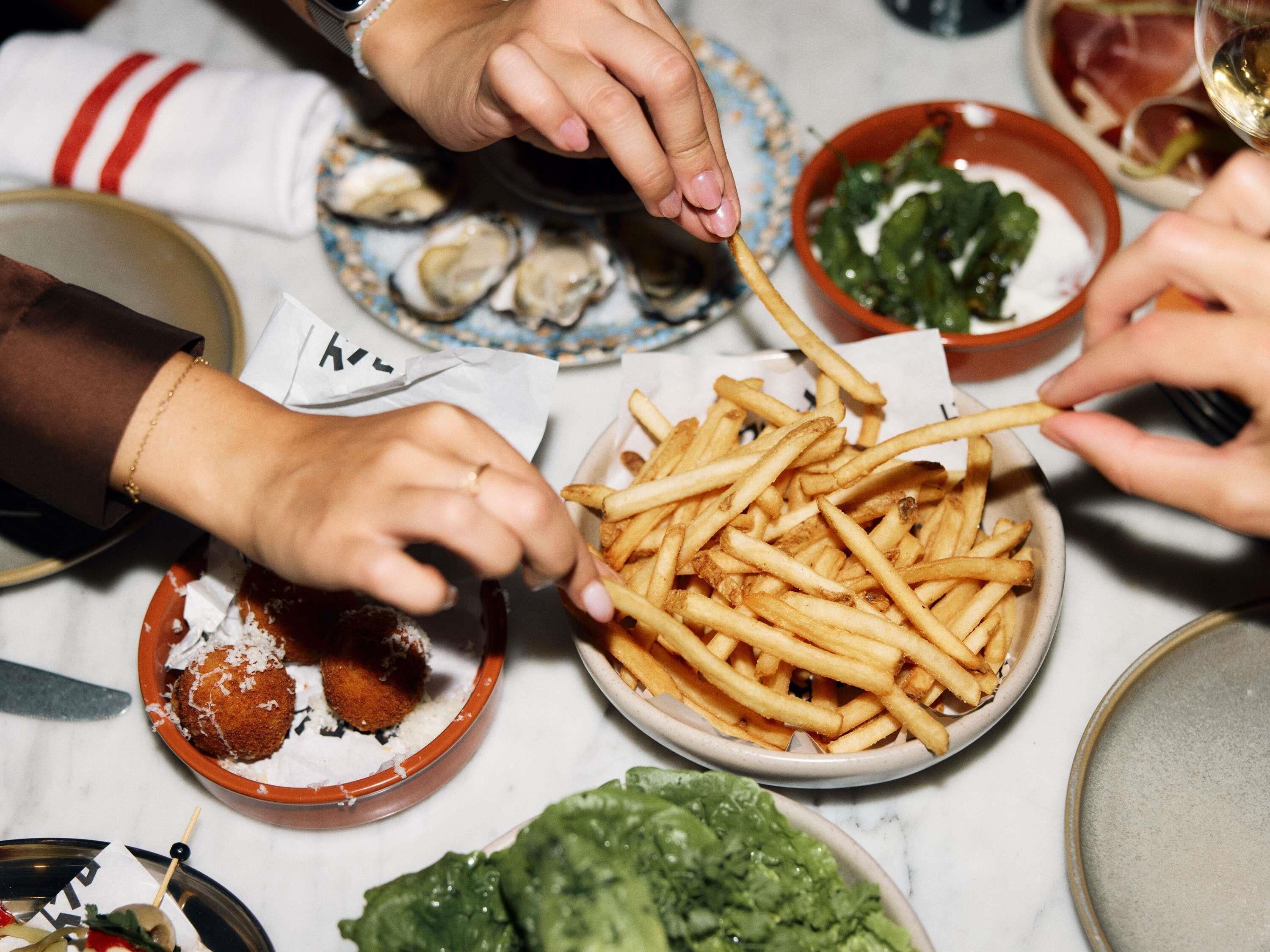 A dining table with various dishes including fries, a salad, and a bowl of what appears to be a seafood dish.
