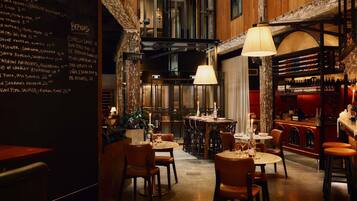 L’intérieur d’un restaurant, avec un menu affiché au mur, des tables dressées et un coin bar.