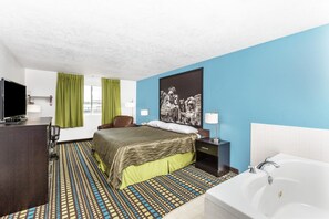 A hotel room with a bed, a desk with a TV, a bathroom with a bathtub, and a large window with curtains. - Super 8 by Wyndham North Sioux City (North Sioux City)