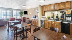 A kitchen with wooden cabinets, a dining area with a table and chairs, a refrigerator, a coffee maker, and a microwave.