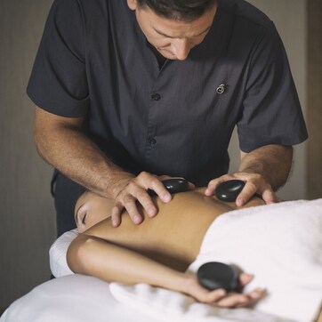 A massage therapy session in progress with a therapist using a massage tool on a client's back.