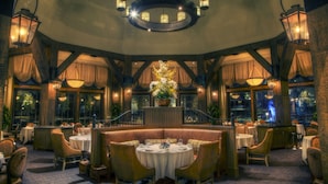 A restaurant with round tables, booths, and a chandelier. - Salamander Resort And Spa (Middleburg)