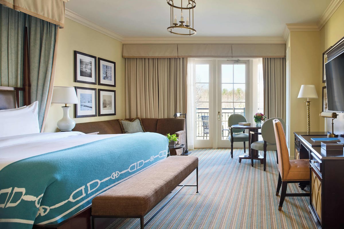 A hotel room with a large bed, a desk, a chair, and a television.