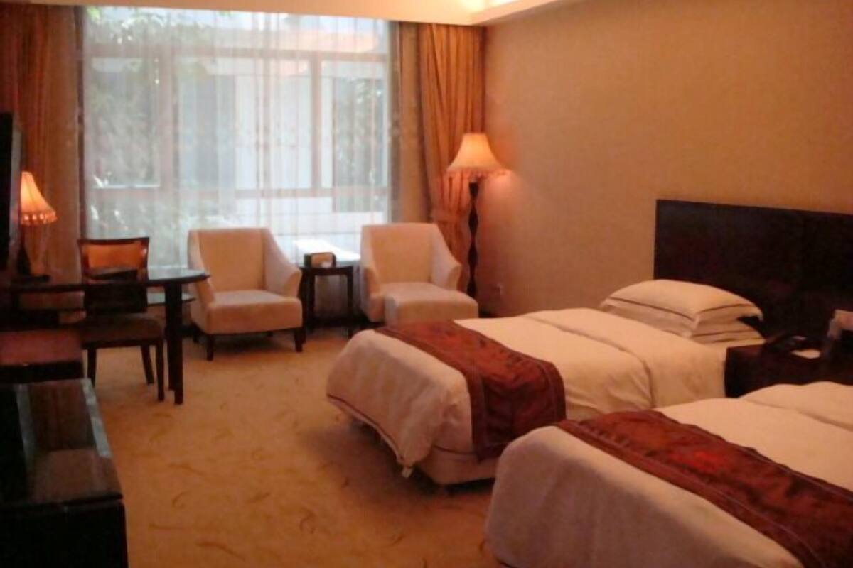 A hotel room with two beds, a desk, a chair, and a window with curtains.