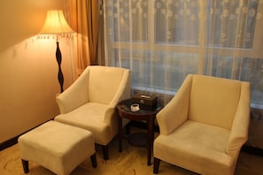Relax in comfort with plush armchairs and a side table, accompanied by a stylish lamp and a convenient ottoman.