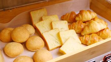 A wooden box containing bread rolls and croissants.