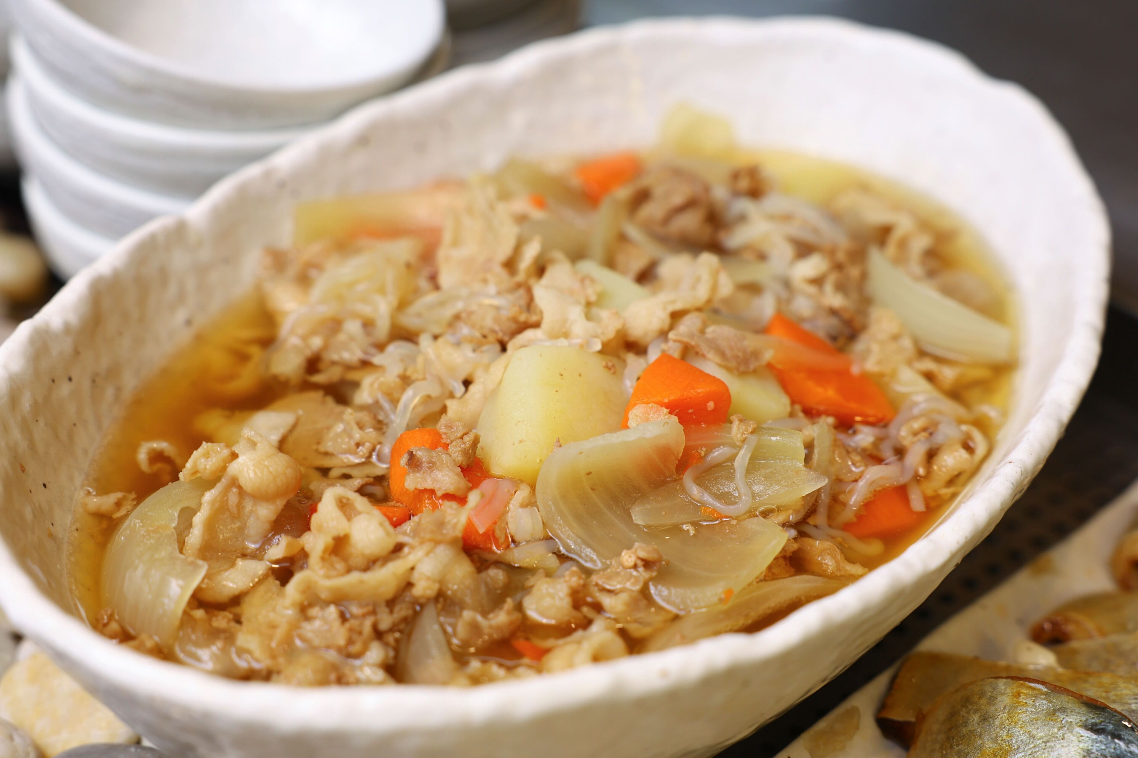Un tazón de sopa con ingredientes visibles como carne, papas y zanahorias.