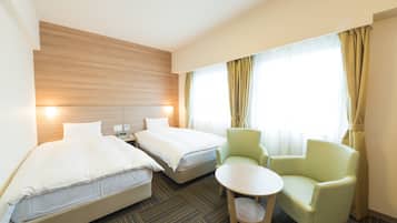 Une chambre d’hôtel avec deux lits, une petite table et une chaise.