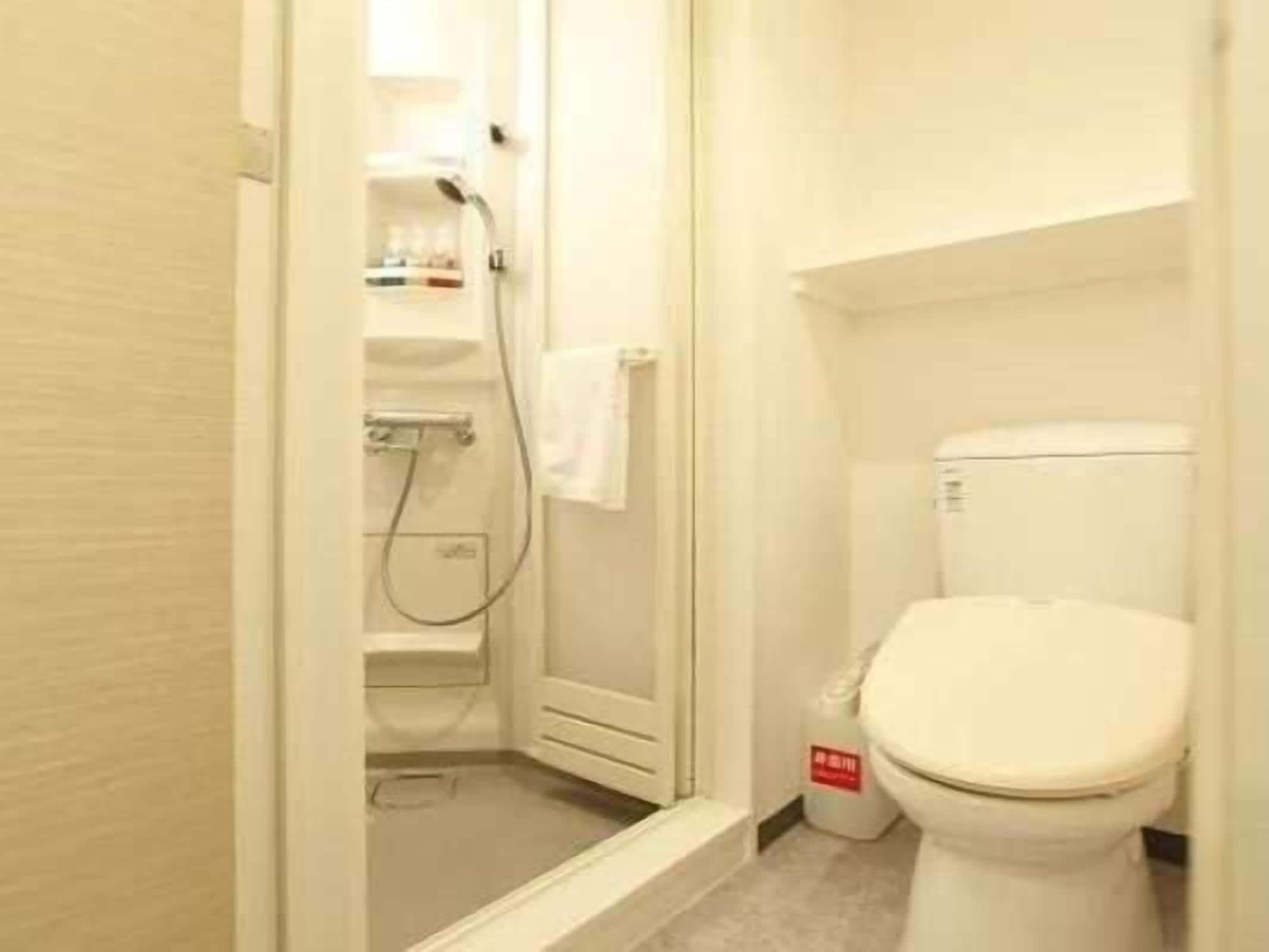 A small, compact bathroom with a toilet, a shower, and a sink.