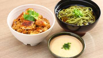 A bowl of food with a green garnish, a bowl of noodles, and a small bowl of soup.